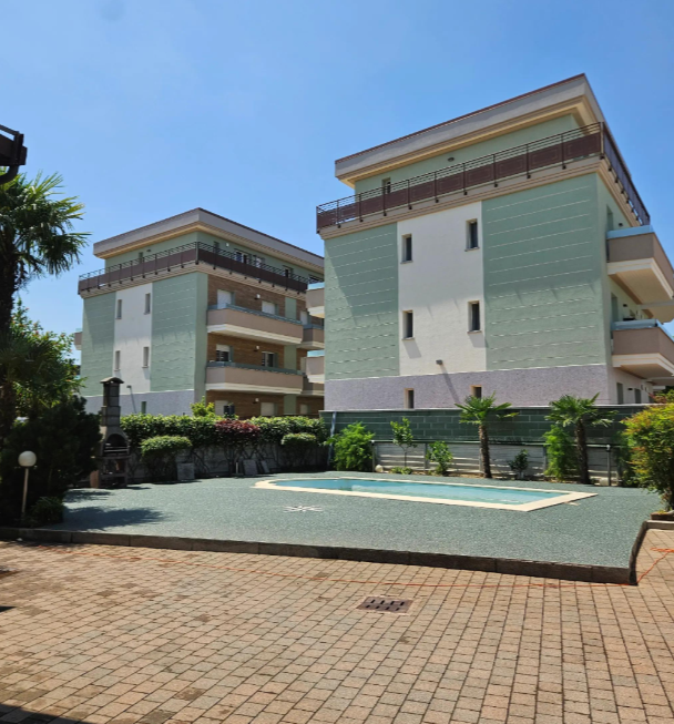 Cortile condominiale con piscina e pavimento in graniglia