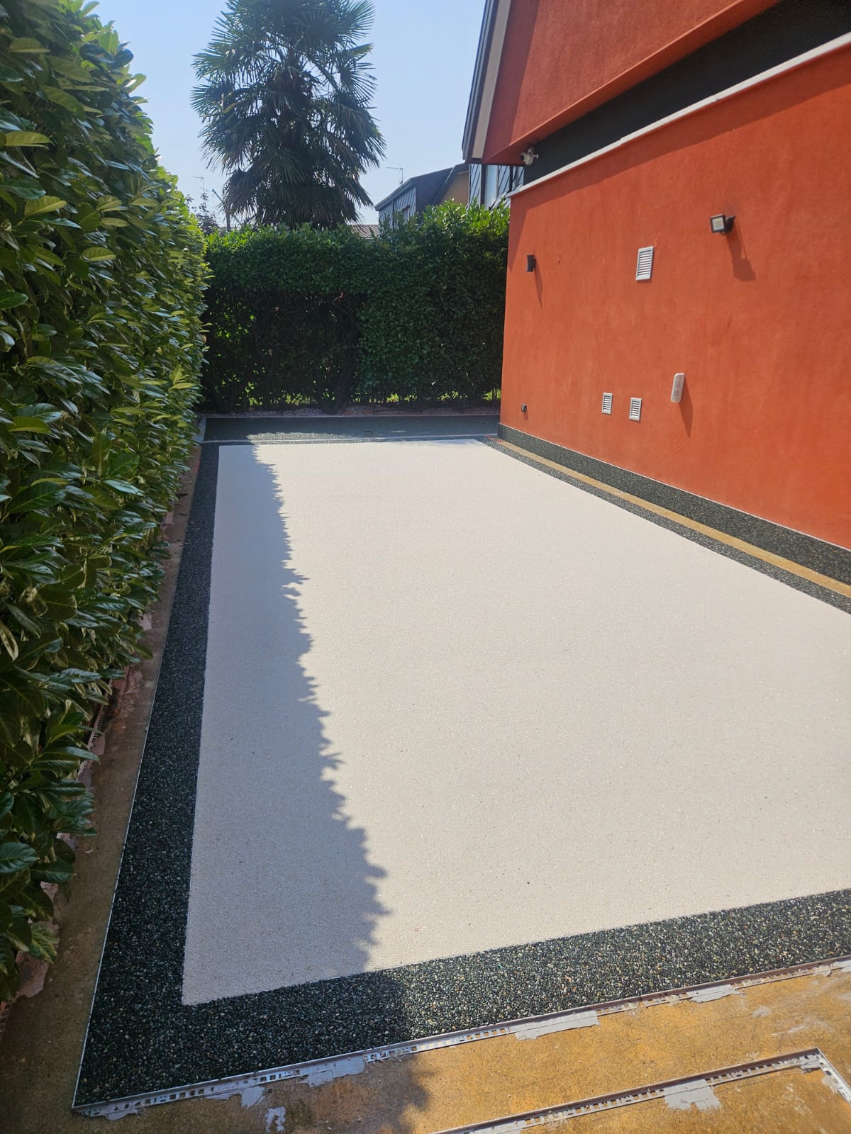 Passaggio laterale in graniglia chiara con bordo scuro di contrasto
